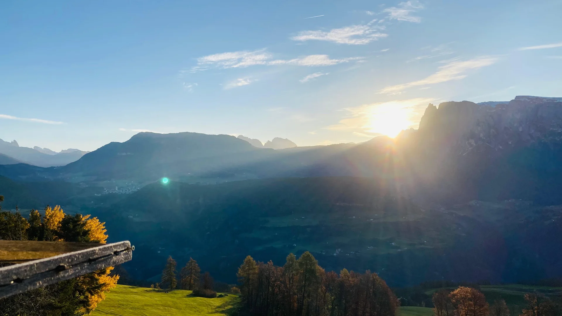 Ferienwohnung am Ritten: Armonia, Hof mit Musik Abendsonne über einem Bergtal mit grünen Wiesen und Holzzaun