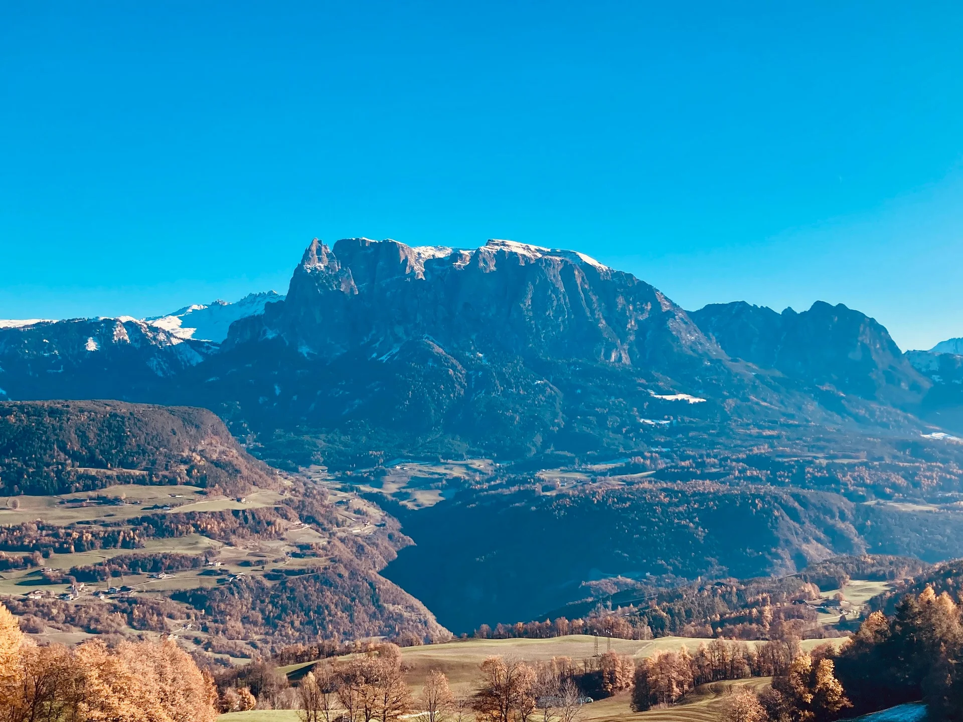 Ferienwohnung am Ritten: Armonia, Hof mit Musik Blick auf ein herbstliches Tal und schneebedeckte Berge unter blauem Himmel